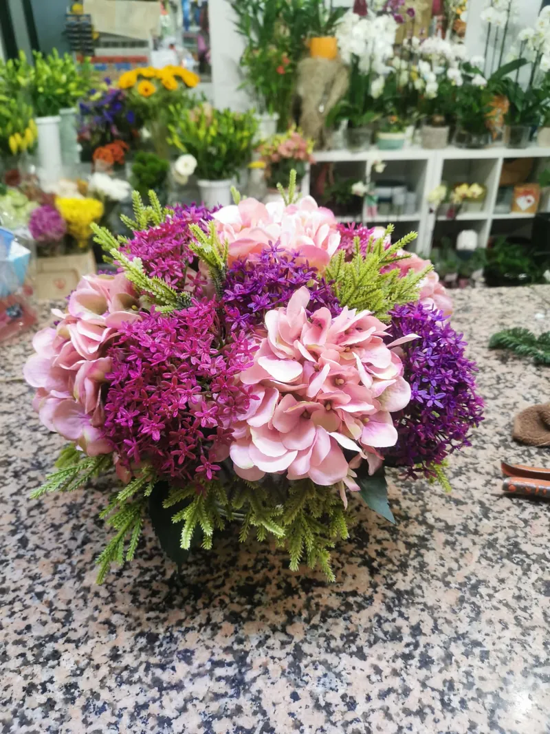 Arranjo de flores artificiais com hortênsias cor-de-rosa e lilases, na loja