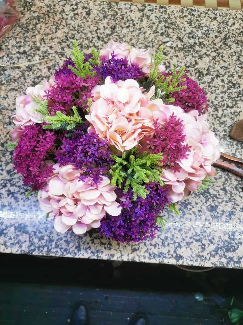 Arranjo de flores artificiais com hortênsias cor-de-rosa e flores roxas