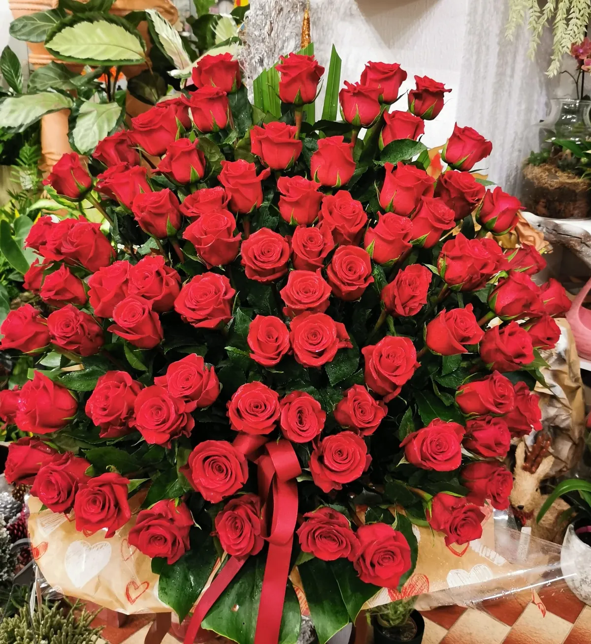 Arranjo em cúpula com dezenas de rosas vermelhas, executado sobre o balcão da loja