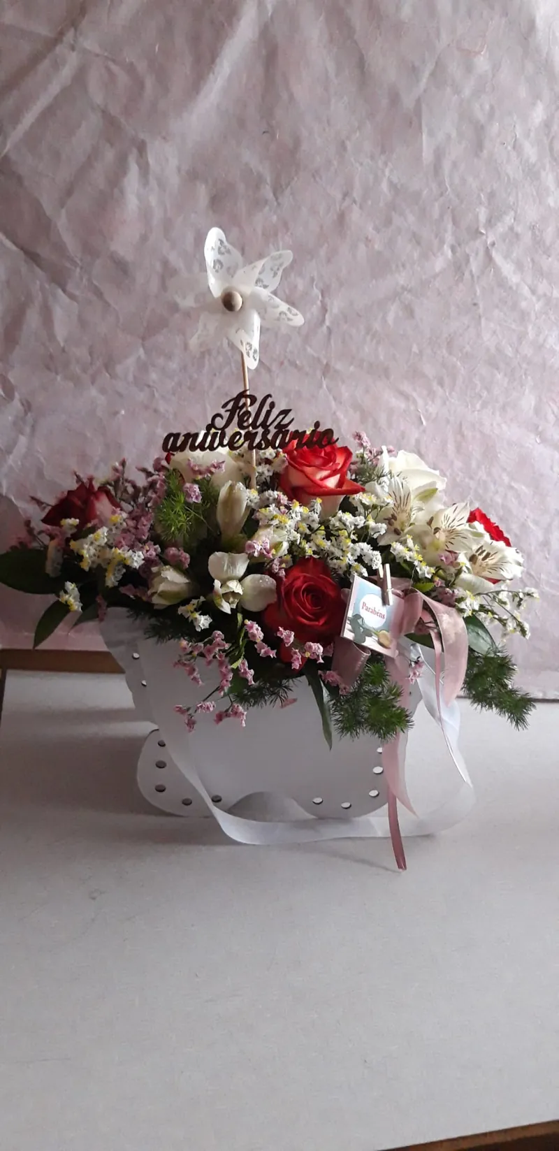 Arranjo em chávena de porcelana branca com rosas vermelhas e flores brancas