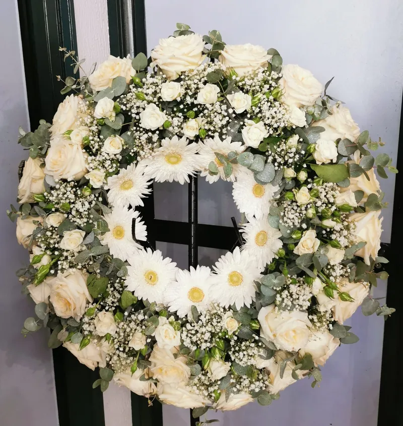 Coroa de funeral em rosas e gérberas brancas com eucalipto