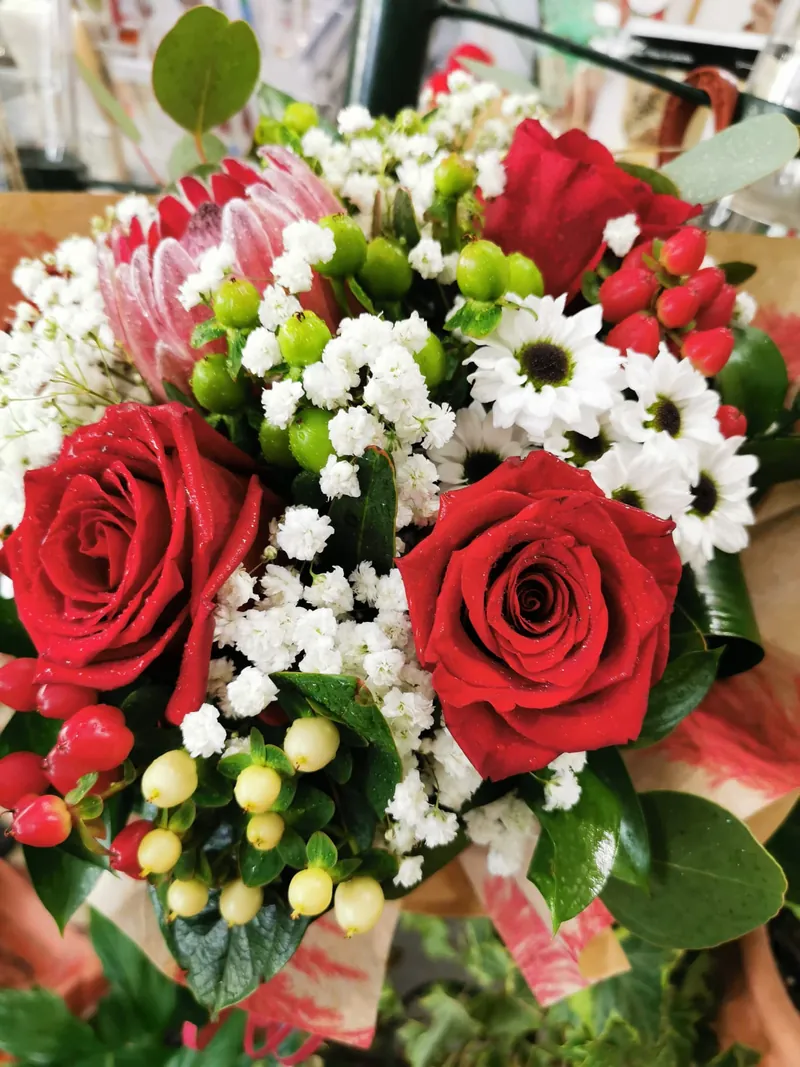 Pormenor de ramo com rosas vermelhas, margaridas brancas e hypericum